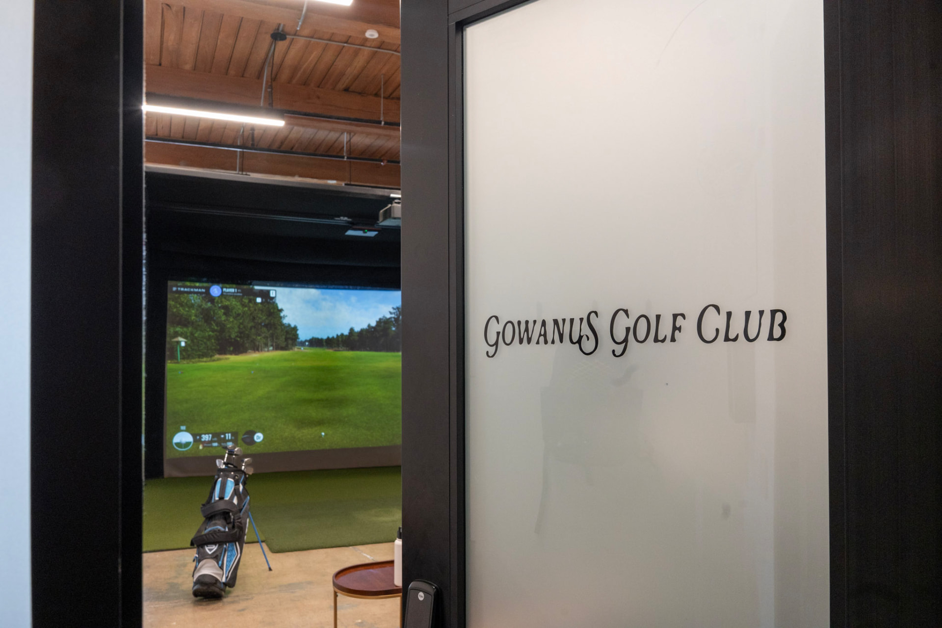 Frosted glass door with Gowanus Golf Club lettering, Trackman bay beyond