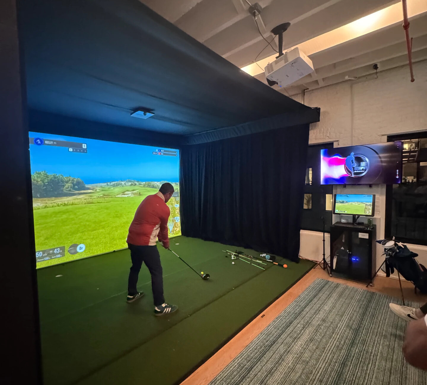 Prospect Heights simulator bay with a member in a red jacket and the projector screen